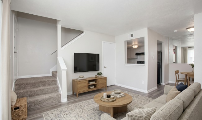 living space with grey floors, stairs, and kitchen